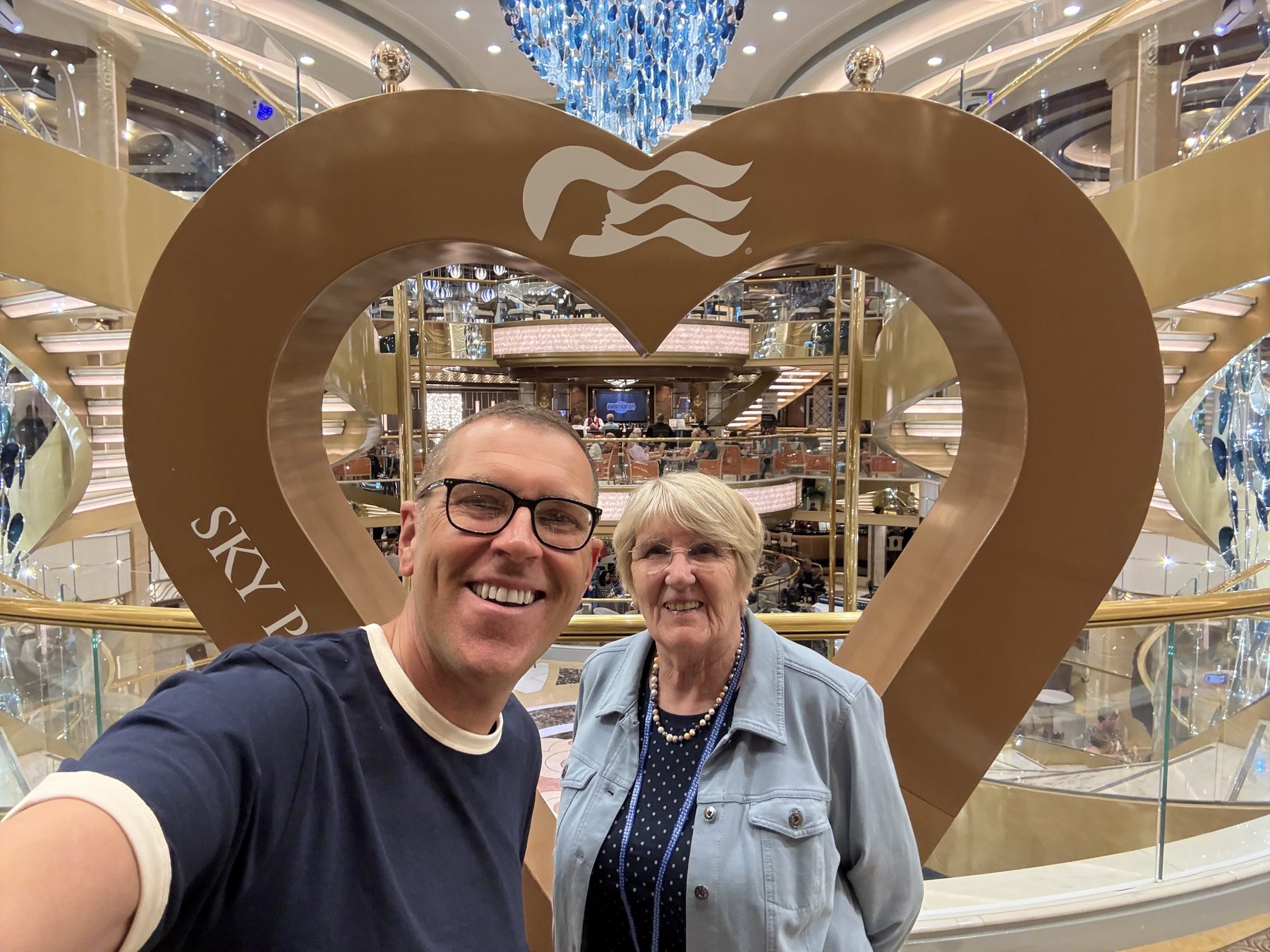 Frances framed by a heart sculpture in the Sky Princess atrium