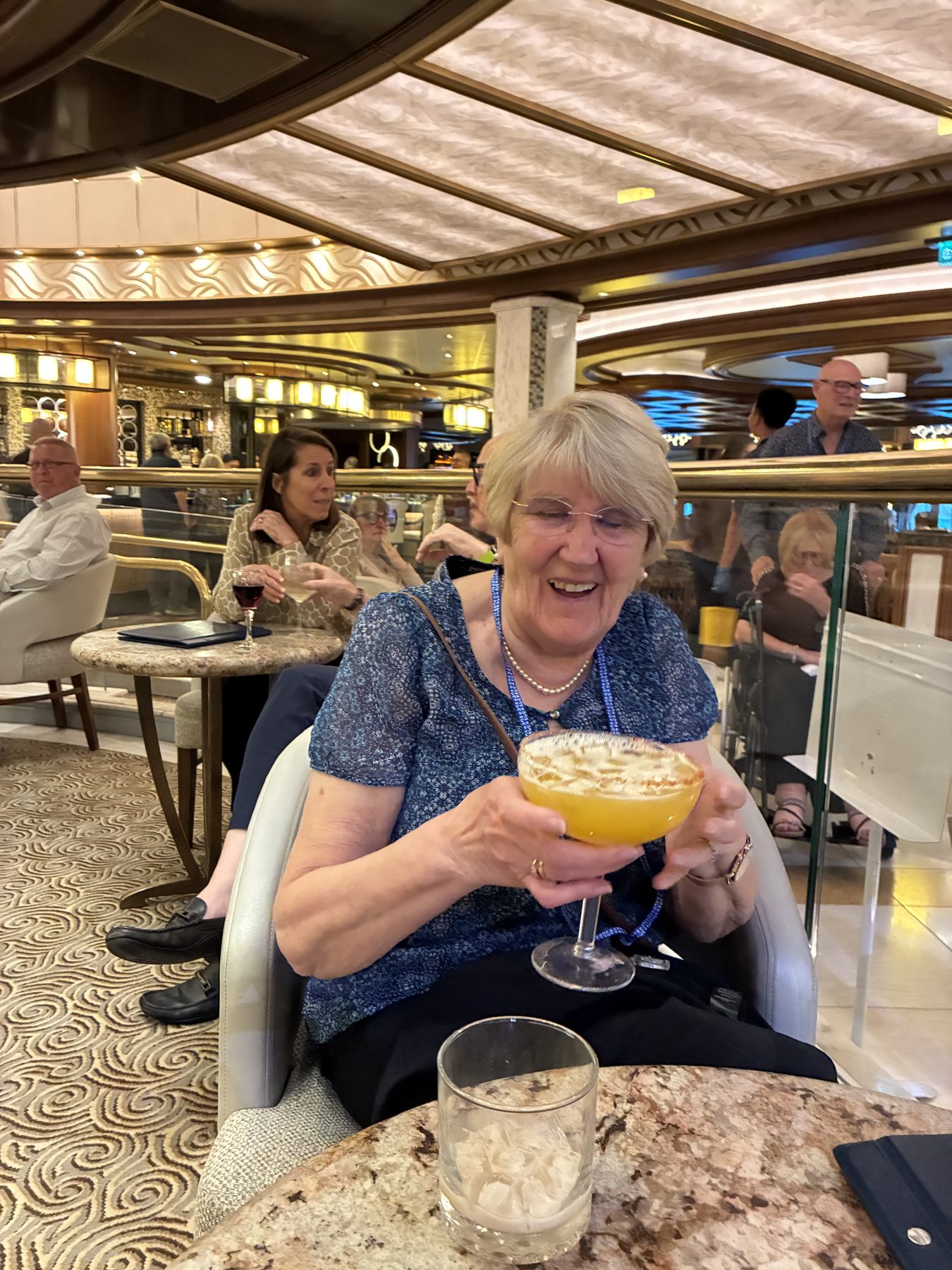 Frances laughing as she holds an enormous goblet cocktail