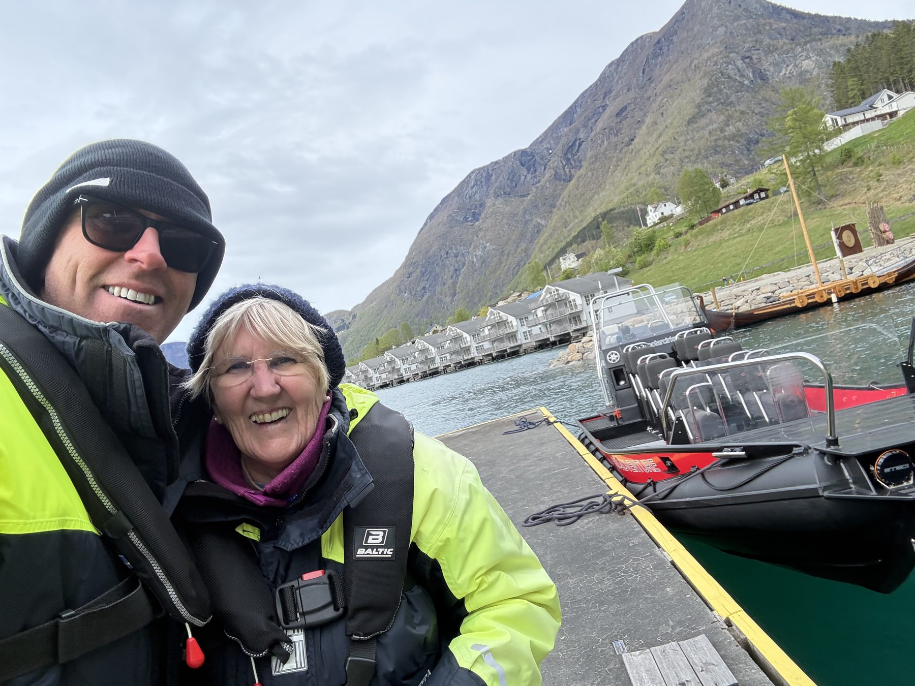 Stuart and Frances at the dock, life vests on, polarcirkel RIB and viking longboats behind