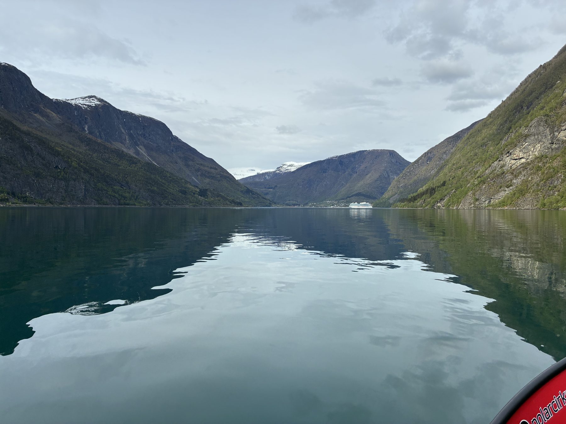 View from the RIB looking down the Sognefjord, mirror-still water reflecting the mountains, Sky Princess tiny in the distance