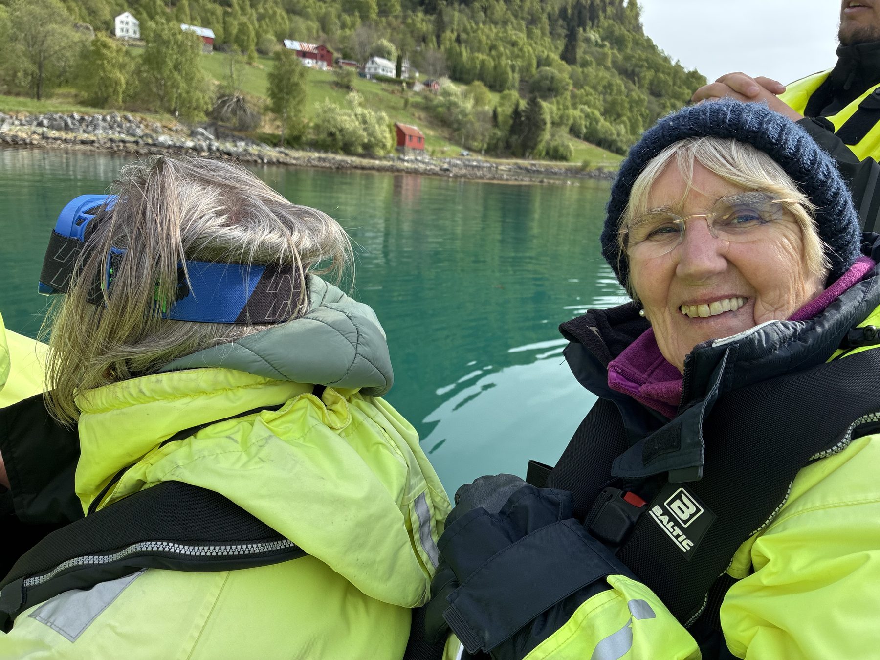 Stuart and Frances together in the boat, fjord water and a Norwegian farmhouse behind